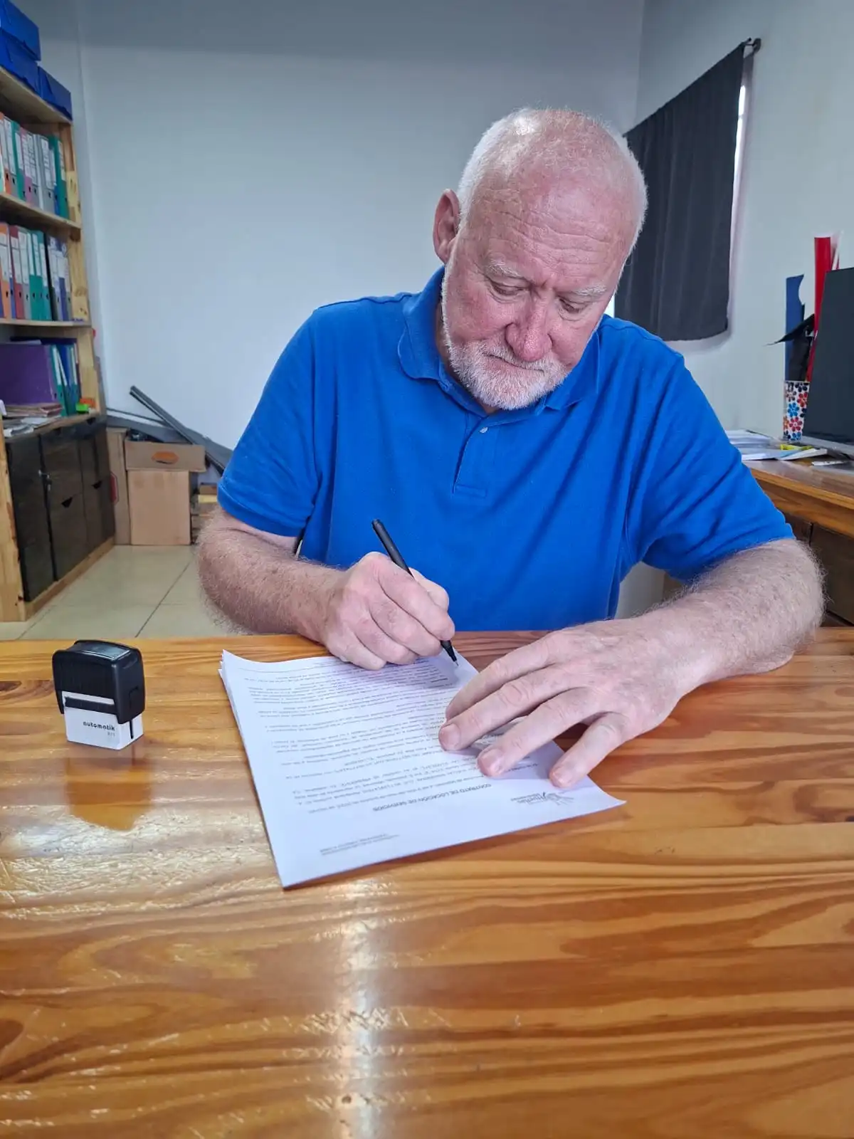 Juan Carlos Otto firmando un contrato en su oficina